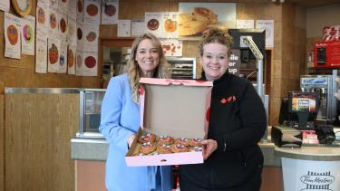 two women smiling holding a box of cookies