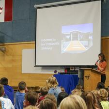 Female principal stands in front of school assembly