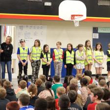 Joy and Kindness club students stand in front of school assembly