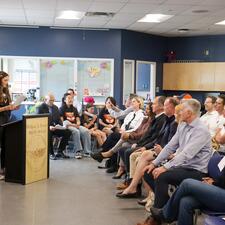 Female student stands at podium in front of audience, speaking about the project